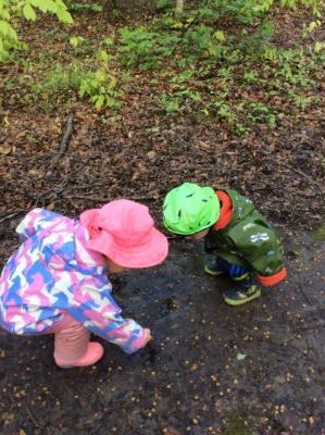 Two children crouched down, investigating something in the mud.
