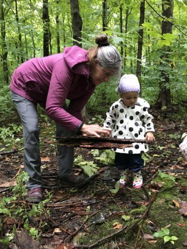 Educator and toddler observing bark closely while exploring forest textures.