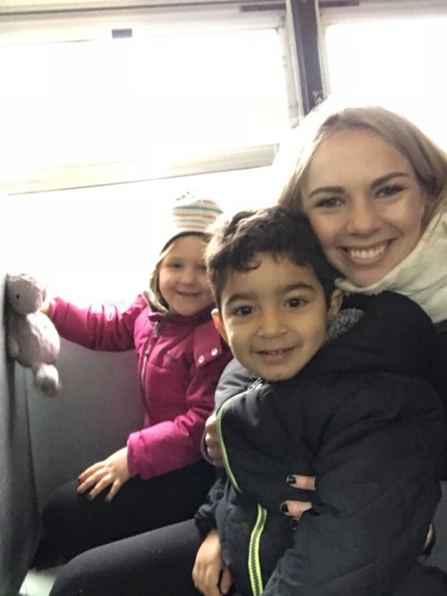 Adult and children smiling on a school bus during the field trip to Seneca College.