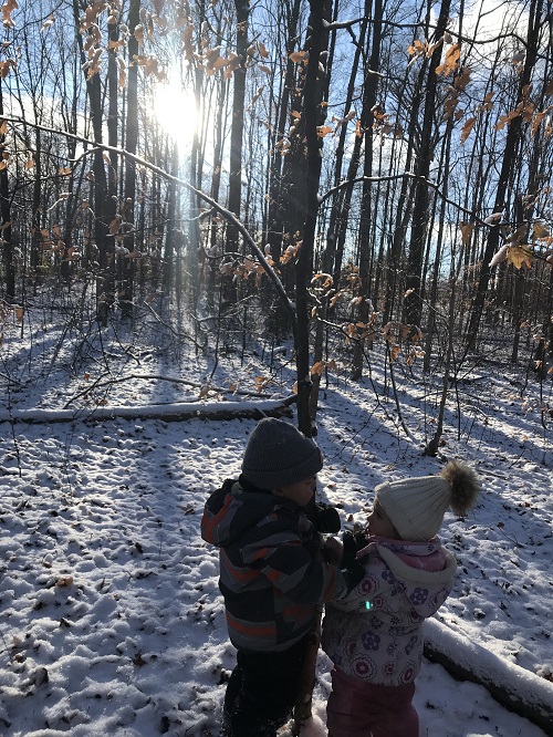 two children facing each other on a snowy forest trail
