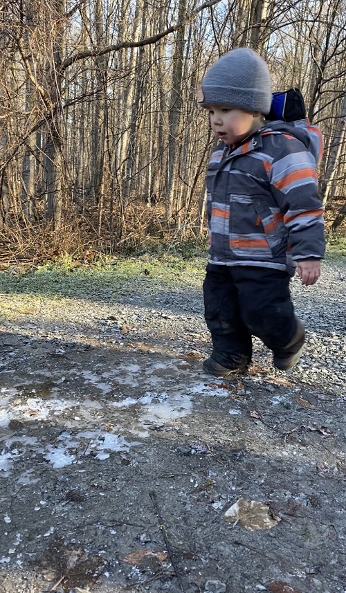 Child walking on puddles that have turned to ice
