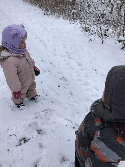 two children standing on a snowy forest trail