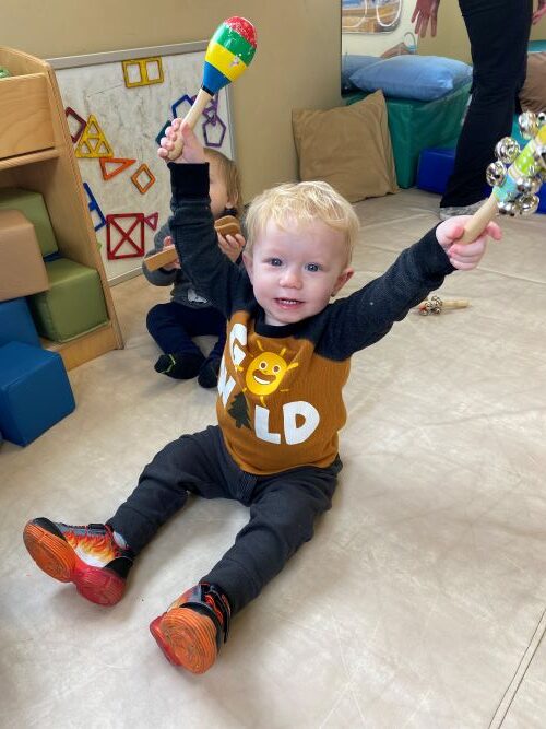 Little boy holding up musical shakers.