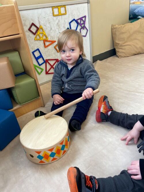 Child playing with a wooden drum.