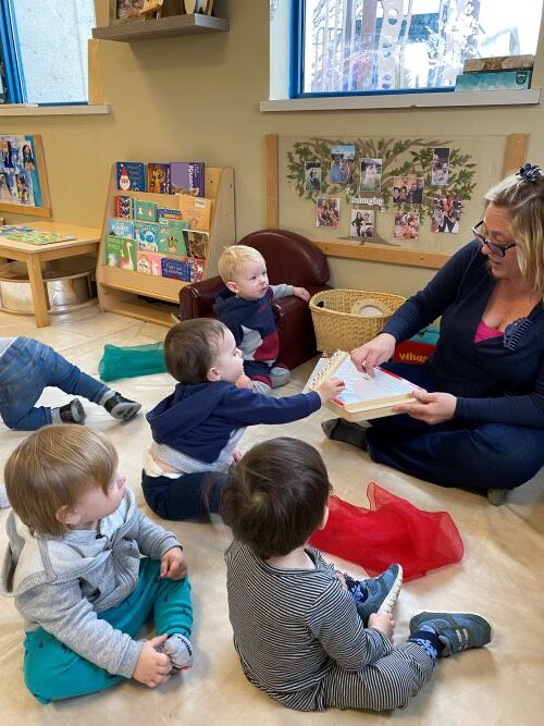 Children gathered around music educator in the classroom.