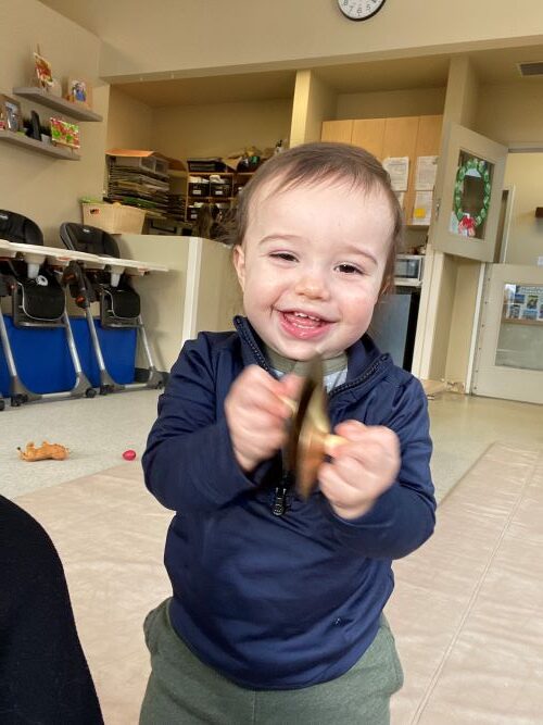 Little boy playing with mini cymbals during music time in the classroom.