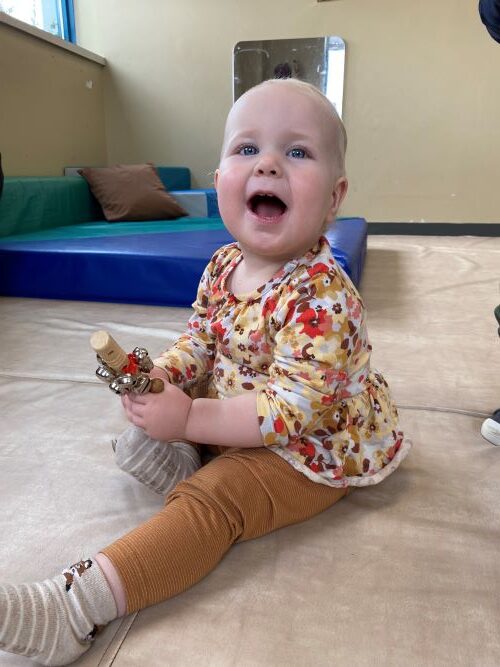 Little girl playing happily with musical shaker.