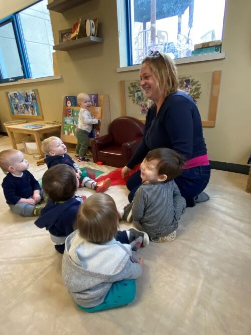 Children gathered around music educator in the classroom.