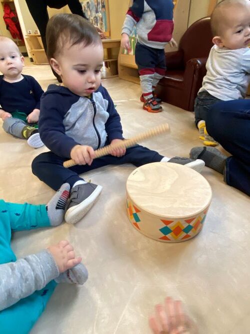 Little boy playing with a wooden drum.