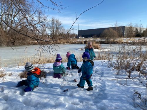 Children outside in winter playing in the snow looking out to the frozen lake.