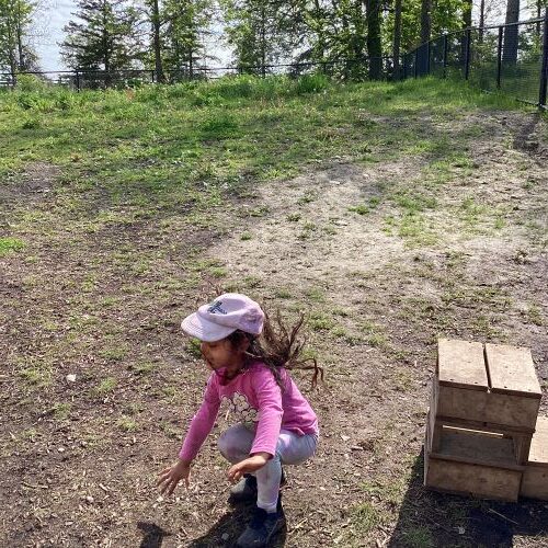 Girl has landed on the ground after jumping off a small wooden block.