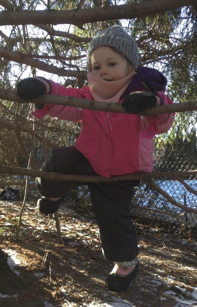 Toddler standing on a branch, confidently preparing to climb further up.