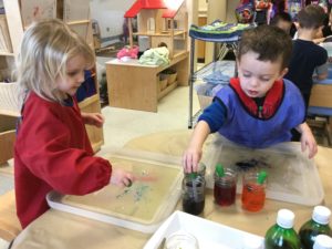 Two children at table, using droppers to mix colours.