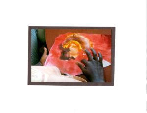 Closeup of Uganda child's hand touching colourful painting.