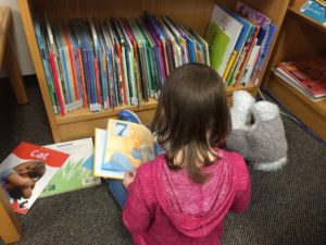Child sitting on floor flipping through a picture book.