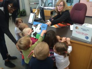 Group of children at library counter checking out books with librarian.