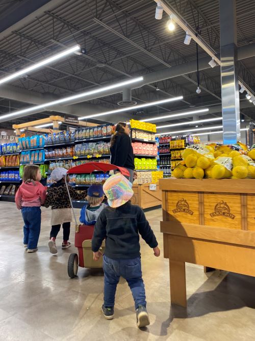 Children in grocery store fruit section.