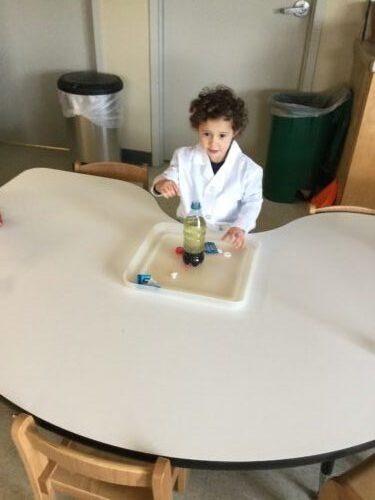 The child in a lab coat continues the experiment.