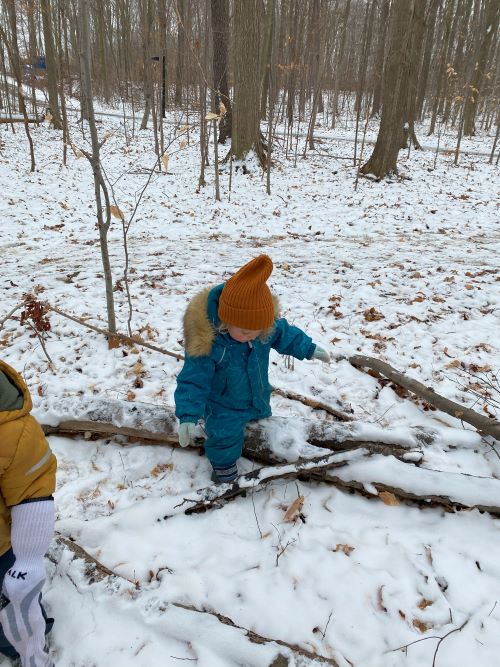 Child playing with sticks in snowy forest
